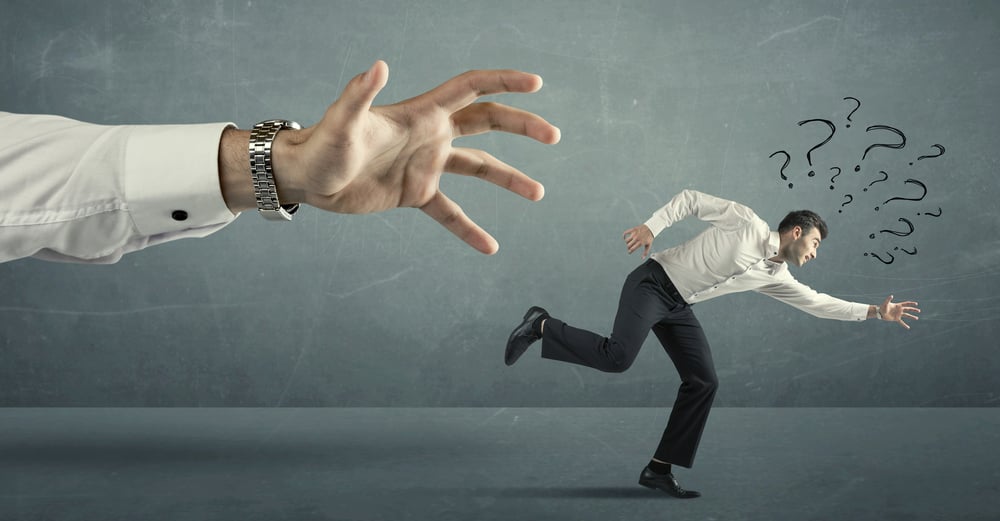 Businessman with question marks running away from a big hand concept on background
